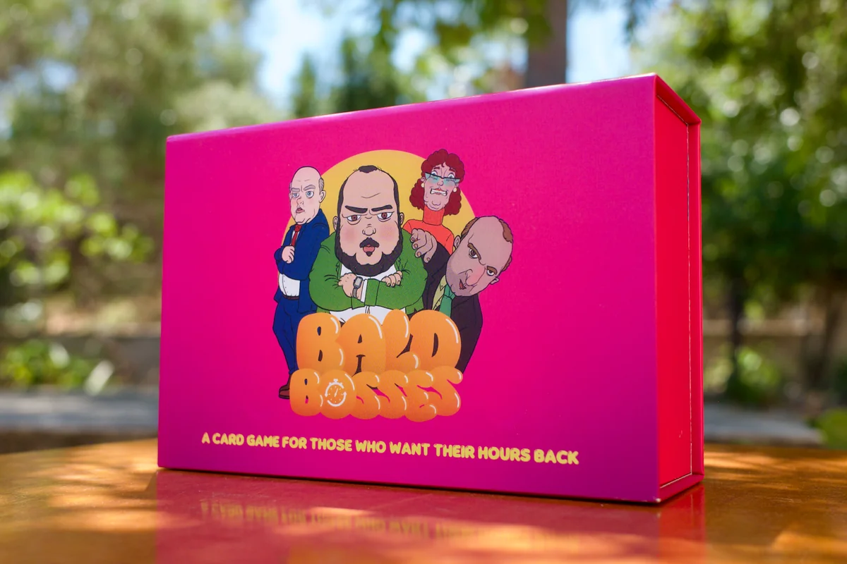 Bald Bosses game box surrounded by colorful cards — orange, aqua, yellow, purple, magenta